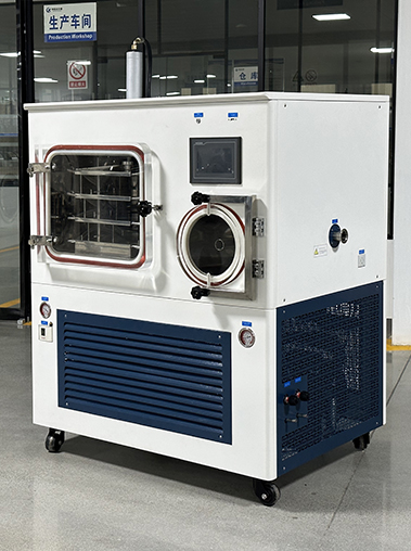 Three-quarter left view real shot of a large industrial lyophilizer vacuum freeze dryer unit on wheels inside a clean manufacturing workshop.